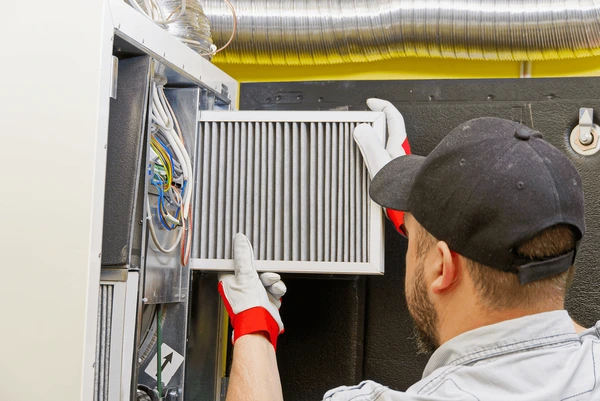 HVAC technician replacing furnace filter in Shelby Township MI